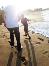 Father and son standing on beach against sky