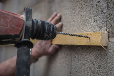 Close-up of drill machine drilling wood on wall