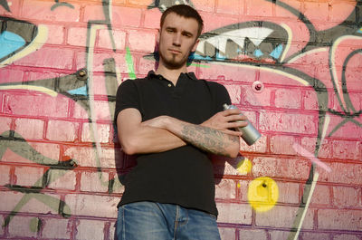 Full length of young man standing against graffiti wall