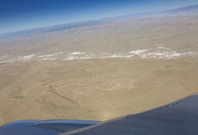 Aerial view of airplane wing over landscape against sky