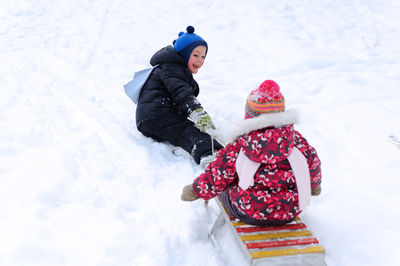 Cute kids playing on snow covered land during winter