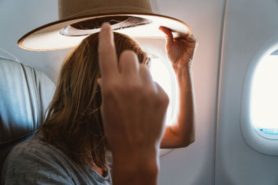 Woman putting on hat in the airplane