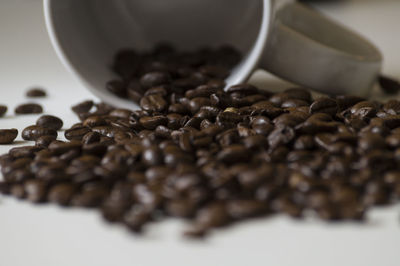 Close-up of roasted coffee beans and cup on table