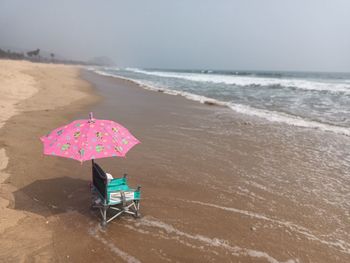 Deck chairs on beach against sky