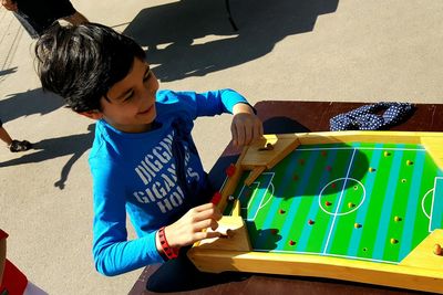 High angle view of cute smiling boy playing soccer board game on street