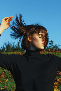 Young woman standing on field standing against clear blue sky