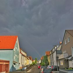 Cars on street by houses against sky