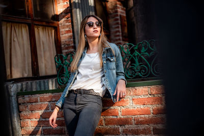 Portrait of young woman standing against wall