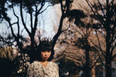 Portrait of woman looking away against trees