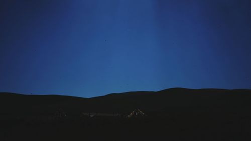 Scenic view of silhouette field against clear blue sky at night