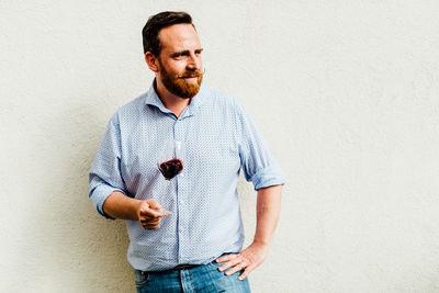 Caucasian man holding glass of red wine on neutral background