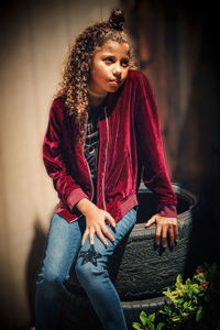 Young woman looking away while sitting outdoors