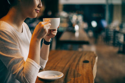 Midsection of woman drinking coffee at restaurant