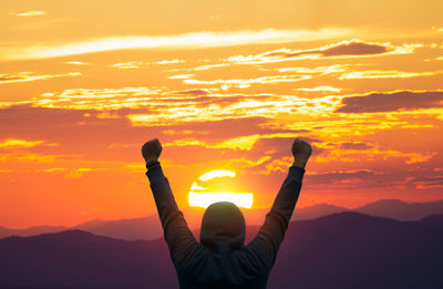 Rear view of silhouette woman standing against sky during sunset