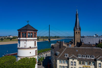 Church amidst buildings against clear blue sky