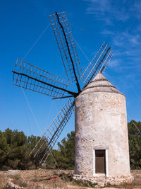 Low angle view of traditional windmill on field against blue sky