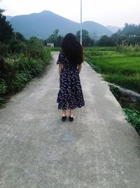 Rear view of woman standing on country road