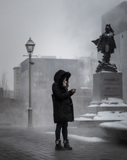 Full length of man standing on street in foggy weather