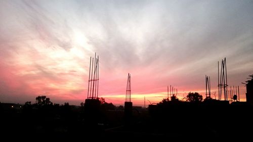 Silhouette cranes against sky during sunset