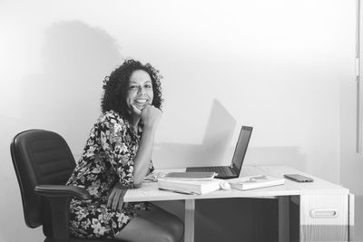 Black and white portrait of a woman sitting working remotely from her home. 