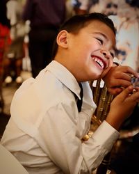 Side view of smiling boy holding camera