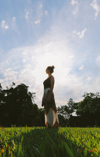 Full length of woman standing on grass against sky