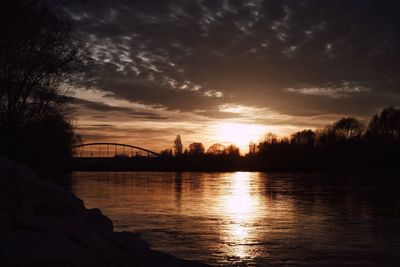 Silhouette bridge by trees against sky during sunset