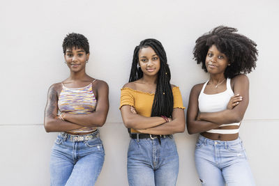 Female friends with arms crossed leaning on wall