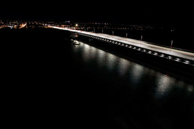 Illuminated bridge over river in city at night