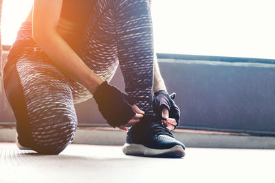 Low section of woman tying shoelace