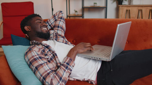 Man using laptop while sitting on sofa at home