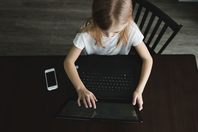 High angle view of girl using laptop computer at table