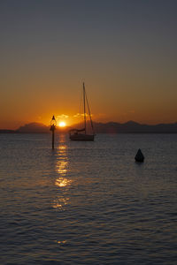 Silhouette sailboat in sea against sky during sunset