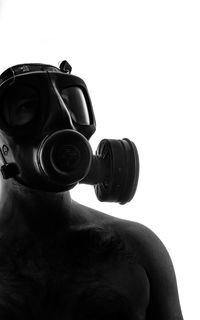 Close-up of shirtless man wearing gas mask against clear sky