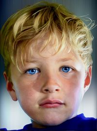 Young boy with blue eyes and blonde hair, stares through camera lens.