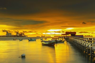 Boats moored at harbor against sky during sunset