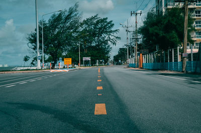 Road amidst trees against sky in city