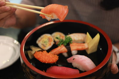 Midsection of person holding sushi in container
