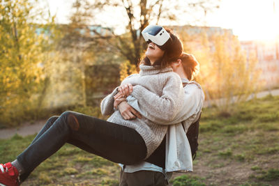 Couple using virtual reality simulator while standing at park