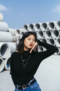 Beautiful young woman standing against sky