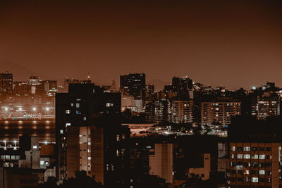 Illuminated buildings in city against sky at night