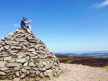 Low angle view of woman standing on rock against clear sky