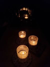 High angle view of illuminated tea light candles in darkroom