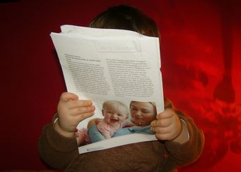 Close-up of baby boy holding magazine while sitting on sofa