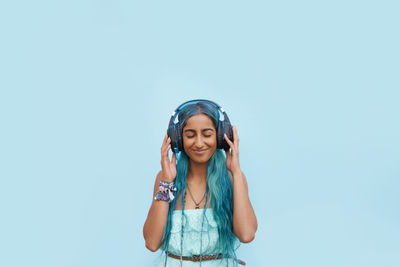 Portrait of young woman standing against blue background