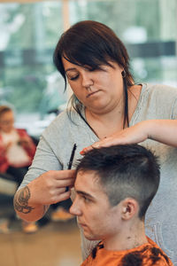 Woman cutting man hair in salon