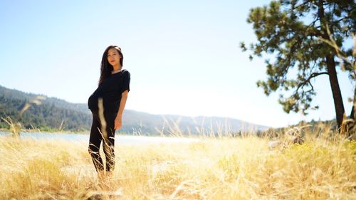 Full length of young woman on grassy field against clear sky