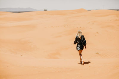 Woman walking on desert in sunny day