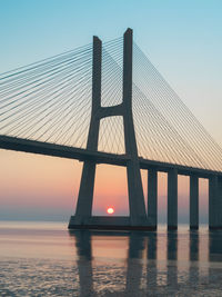 Bridge over sea against clear sky during sunset