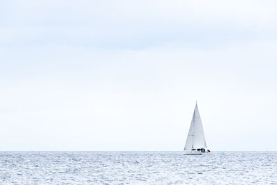 Sailboat sailing on sea against sky